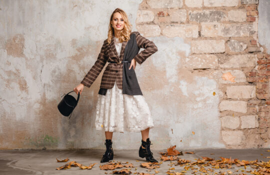 attractive stylish blonde woman in checkered jacket coat walking, autumn fashion trend