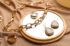 Stylish golden bijouterie and mirror on light brown fabric, closeup